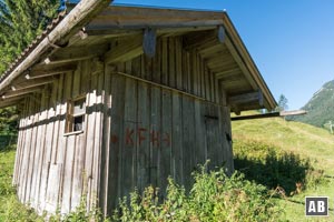 An den Holzschuppen rechtsschwenkend gegen eine Wiese (im Bildhintergrund) ansteigen