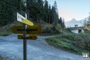 ...und einem Wegweiser. An dem Gebäude vorbei, hinein in den Wald