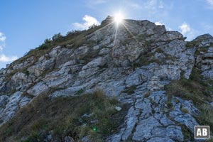 An dieser Stelle des Nordostgrates verleiten Pfadspuren und eine farbige Markierung in die Westflanke zu steigen (rechts im Bild). Das ist der falsche Weg! Hier kommt man sehr schnell in sehr schweres Gelände. Der Steinmann (siehe roter Pfeil) markiert den richtigen Weg und der Aufschwung dahinter muss direkt erklettert werden (I).