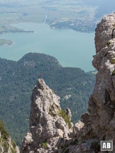 Imposanter Ausblick aus dem Grat auf eine kreuzgeschmückte Felsnadel mit Umrahmung des Kochelsees