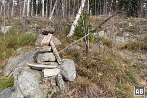 Wenige Meter nach der Linksschleife des Karrenweges verlassen wir den Weg an diesem Steinmann und steigen über dürftige Pfadspuren hoch in den Wald