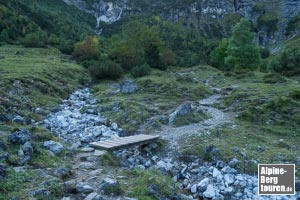 Mittels provisorischer Brücke über ein ausgetrocknetes Bachbett