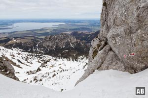 Farbige Markierungen leiten uns durch die Felswände. Den Hintergrund dominiert der Chiemsee.