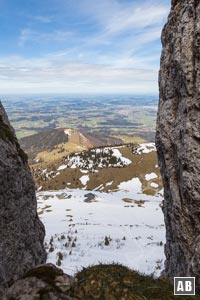 Ein Felsenfenster in den Kaisersälen gewährt Tiefblick auf die Steinlingalm und weiten Ausblick in das Alpenvorland