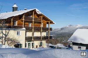 Vorbei am Berghotel Mooshütte geht es über eine große Lichtung eine Fahrstraße nach unten.