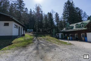 Am Waldrand linksschwenkend, zwischen Toiletten und Gaststätte, hoch zu einer großen Infotafel (links der Bildmitte).