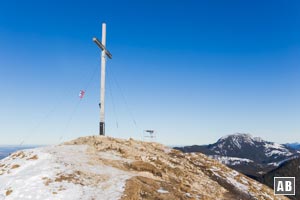 Das Gipfelkreuz des Jochbergs mit der Benediktenwand im Hintergrund