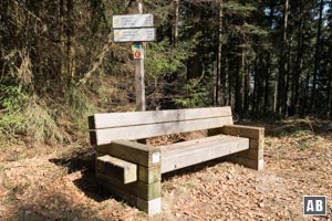 Im Abstieg halten wir uns auf Höhe dieser massvien Sitzbank an den Schotterweg, der nach links wegdreht