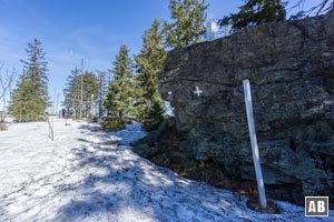 Ein kompakter Felsen mit Grenzstein markiert den Scheitelpunkt des Künischen Grenzkamms. Hier den weiß-blauen Stangen...