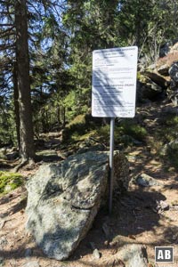 An diesem Hinweisschild verlassen wir die Linie der weiß-blauen Grenzstangen und steigen nach links zu einem Pfad (MarkierungLo1) ab.